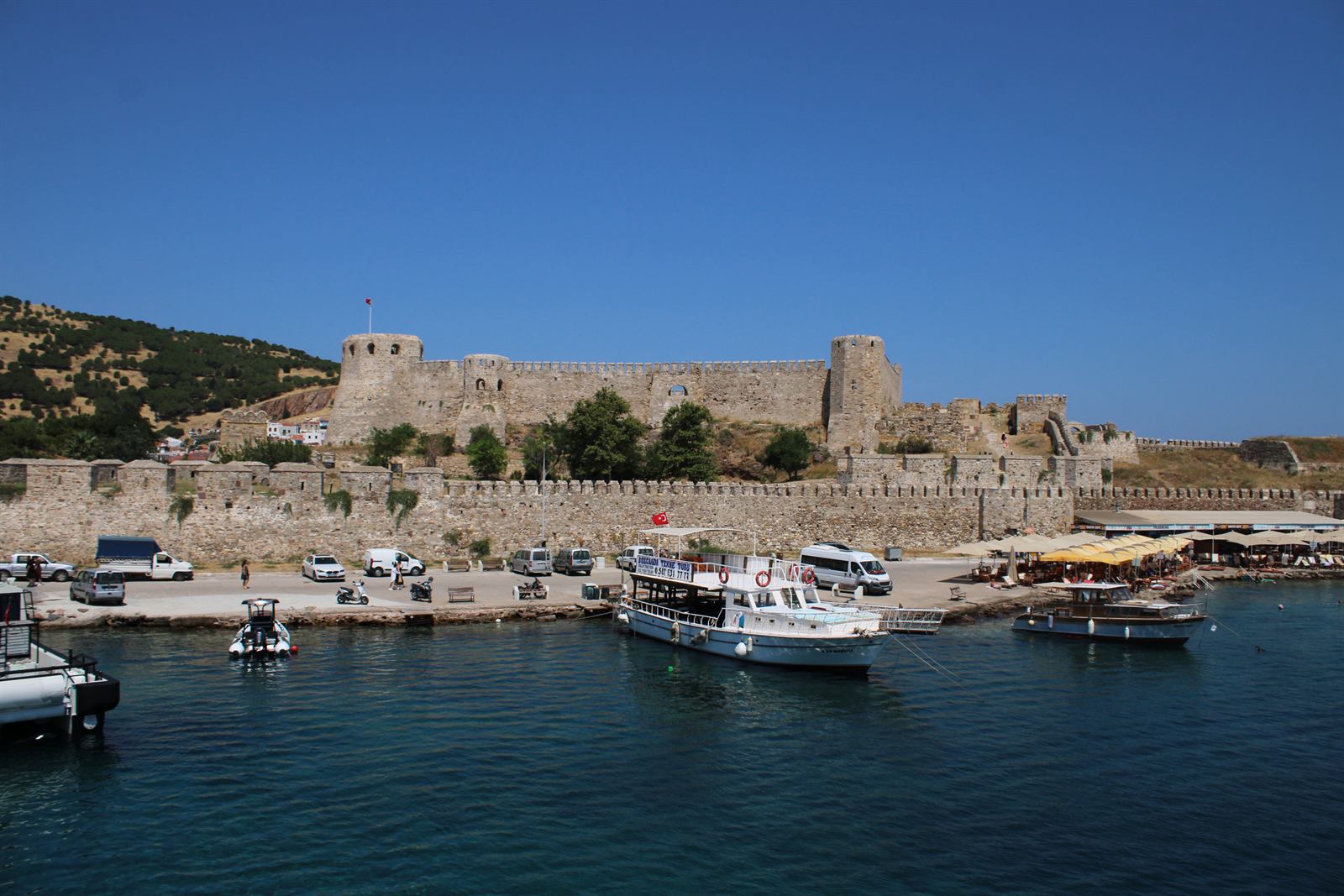 Bozcaada Castle and moored boats beneath a blue sky